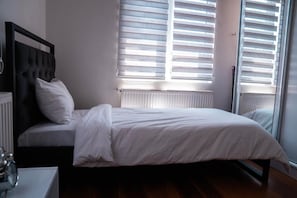 Una camera da letto con un letto, un comodino, un termosifone e una finestra con persiane.