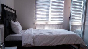 A bedroom with a bed, a bedside table, a radiator, and a window with blinds. - Taxim no 1 Suites Istanbul (Istanbul)