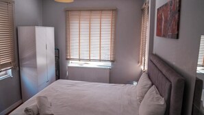 Une chambre à coucher comprenant un lit, une armoire, un radiateur et une fenêtre avec des stores.