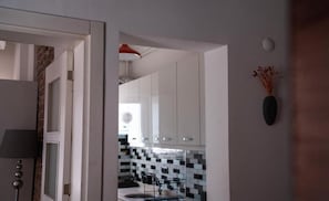 Eine Küche mit weißen Schränken, einer gefliesten Spritzschutzwand und einem schwarzen Stuhl.