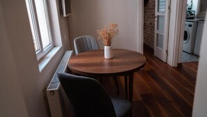 Un coin repas avec une table ronde, un vase contenant des fleurs séchées et une chaise.