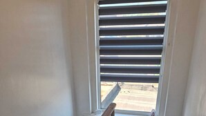 A staircase with a wooden handrail and a window with horizontal blinds.