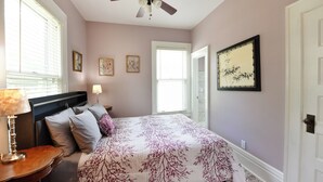 A bedroom with a bed, a nightstand, a lamp, a ceiling fan, and a door. - Historic, dog friendly, 2-BR cottage, walking distance to downtown Baraboo (Baraboo)
