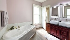 A bathroom with a large bathtub, two sinks, and a vanity with mirrors. - Historic, dog friendly, 2-BR cottage, walking distance to downtown Baraboo (Baraboo)