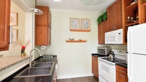 A kitchen with wooden cabinets, a stainless steel sink, a microwave, an oven, and a hanging light fixture. - Historic, dog friendly, 2-BR cottage, walking distance to downtown Baraboo (Baraboo)