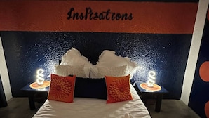 Una habitación de hotel con una cama, dos mesitas de noche y un cabecero que muestra la palabra 'Inspections'.