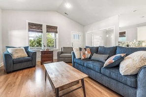 A spacious living room with a large sofa, a coffee table, and a dining area. - Coastal Gem, by the beach and lake (Carolina Beach)