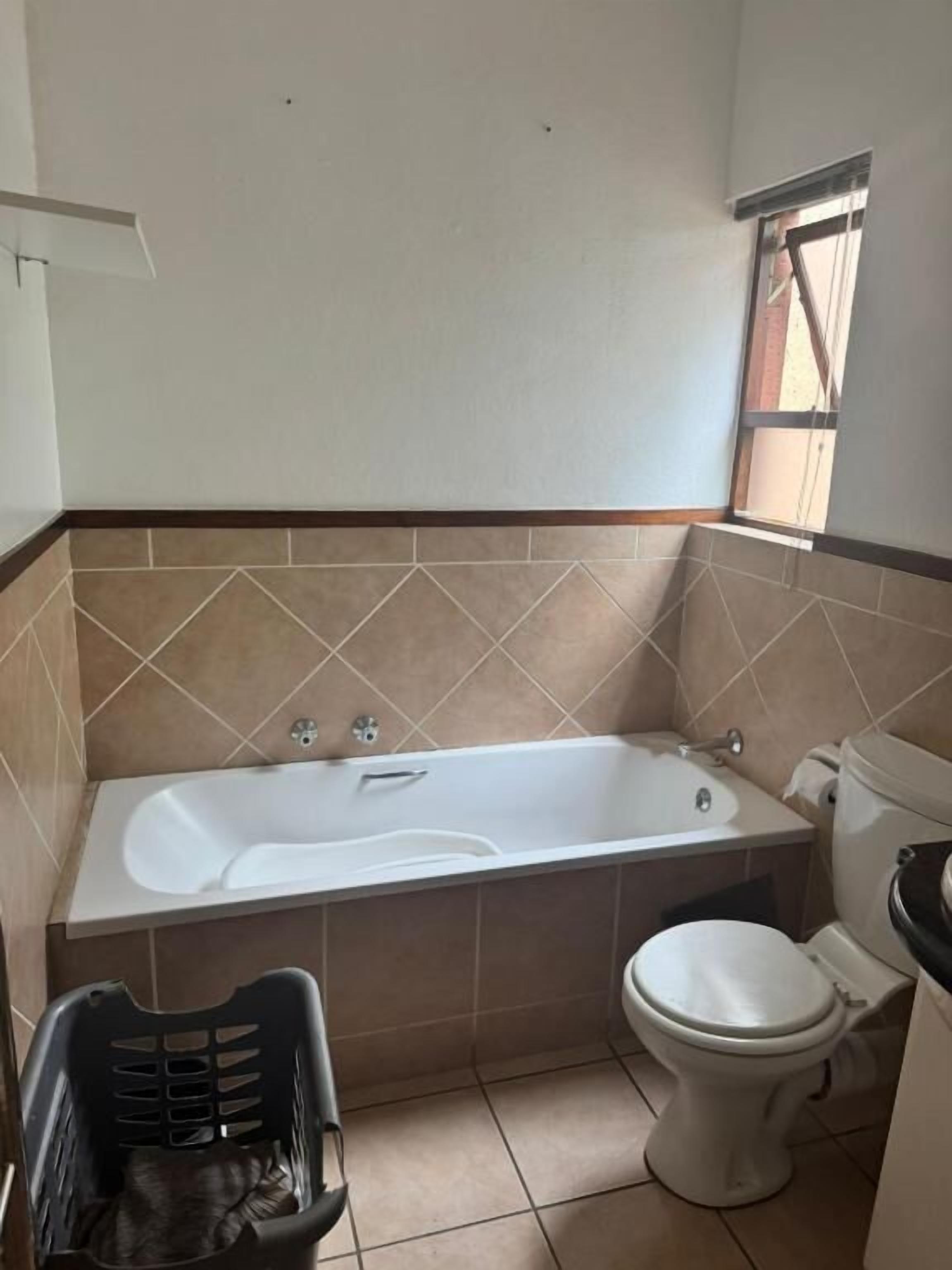 Un baño con bañera, inodoro y ventana.