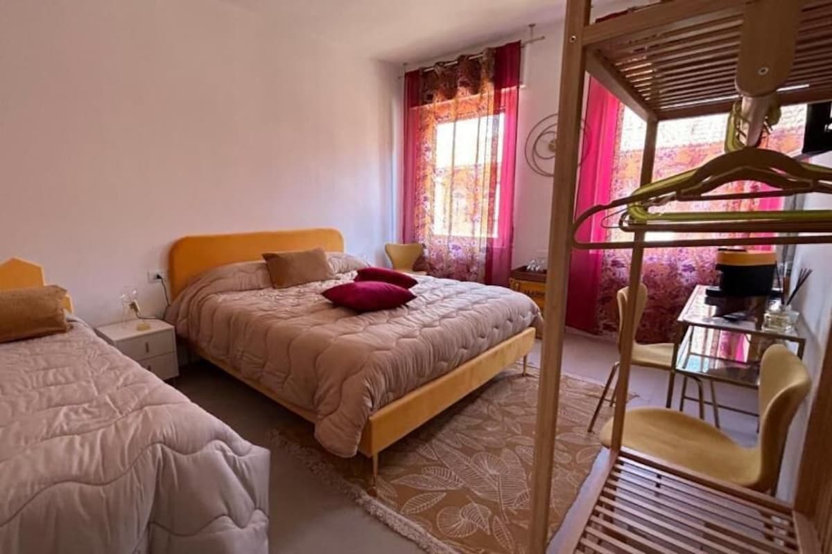Una camera da letto con due letti, una sedia di legno, un tavolo e un appendiabiti.