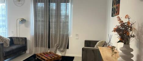 Una sala de estar moderna con un sofá, una mesa de centro, una mesita auxiliar y un jarrón decorativo.