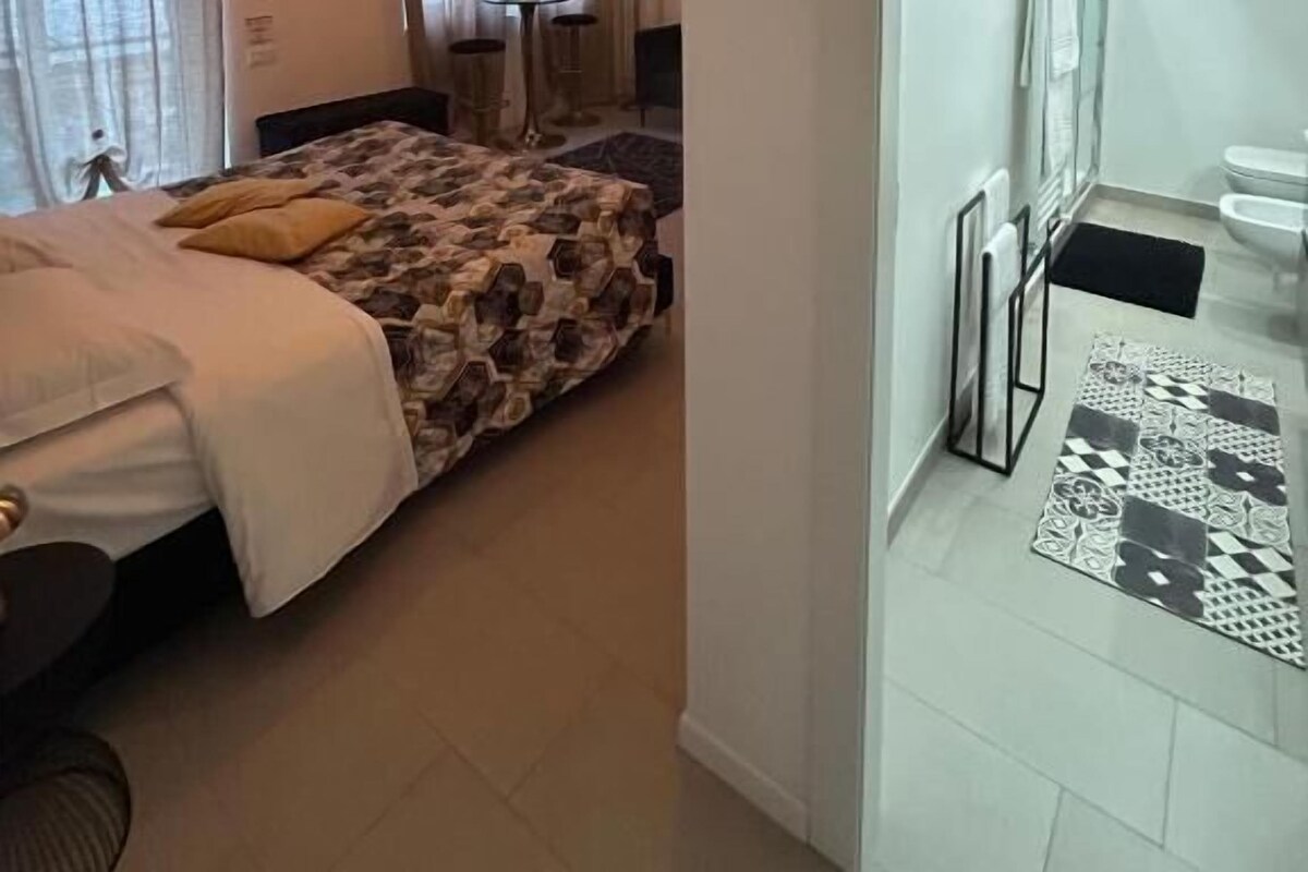 Una camera da letto con un letto, un comodino, una lampada e una finestra con tende.