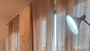 A modern room with a round table, two black chairs, a gold floor lamp, and sheer curtains. - COMFORT ACCOMMODATION SUITE≤ CAMERE (Bergamo)
