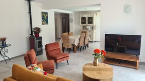 Un soggiorno con divano, poltrona, televisore e zona pranzo con sedie e tavolo.