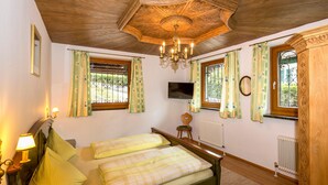 A bedroom with a double bed, two bedside lamps, a television, and a wooden ceiling. - Ferienhaus Höllbacher, Mountian View & Garden (Bad Gastein)