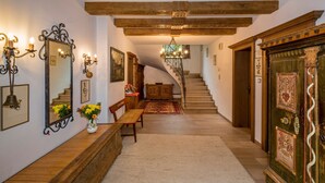 A staircase leading to a second floor, a bench, a mirror, wall sconces, and a chandelier. - Ferienhaus Höllbacher, Mountian View & Garden (Bad Gastein)
