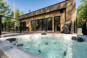 A modern house with a hot tub, large windows, and a patio area. - Private Pool & Spa | Chalet Bella Vista (Saint-Côme)