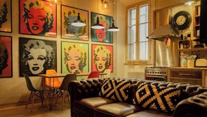 A living room with a leather sofa, a dining table with chairs, and a kitchen area with a stove and cabinets. - BuddyRent - Lucky Jazz - Nomentana - 5 ospiti (Rome)