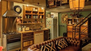 A cozy kitchen with a brown leather sofa, wooden cabinets, a stove, and a refrigerator. - BuddyRent - Lucky Jazz - Nomentana - 5 ospiti (Rome)