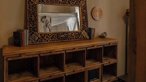 A wooden console table with a large mirror and decorative frame, a speaker, and a round wall decoration. - BuddyRent - Lucky Jazz - Nomentana - 5 ospiti (Rome)