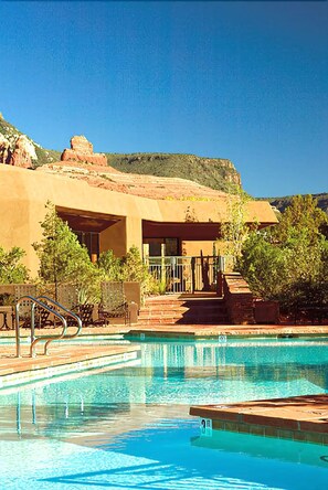 A pool area with a clear view of the pool, steps leading to a covered area, and surrounding vegetation. - Hyatt Pinon Pointe (Sedona)