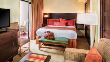 A hotel room with a bed, a television, a desk, a chair, a bench, and a lamp.