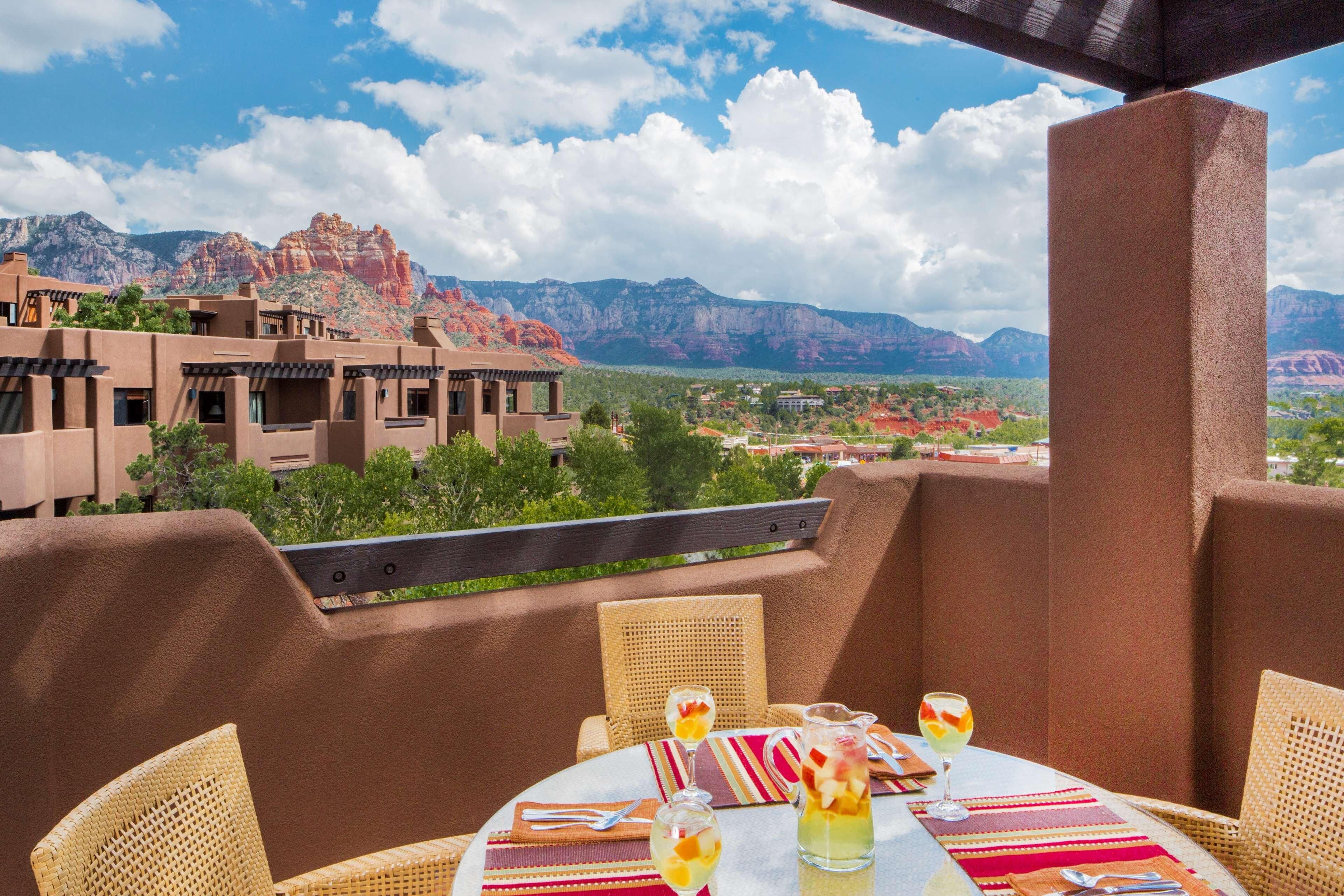 A terrace with a table set for dining, wicker chairs, and a view of red rock formations.