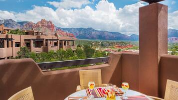 A terrace with a table set for dining, wicker chairs, and a view of red rock formations.