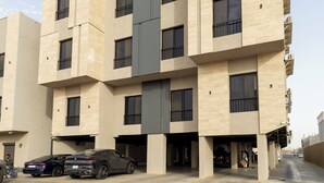 Um edifício de vários andares com um design arquitetônico moderno, destacando um elemento vertical central e diversas varandas.