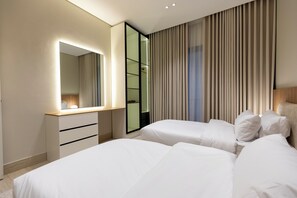A hotel room with a bed, a bedside table, a mirror, and a window with curtains. - Spacious & Charming Stay Smart TV (Madinah)
