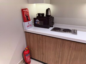 Eine Küchenzeile mit Mikrowelle, Kaffeemaschine und Feuerlöscher.