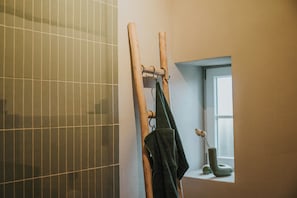 Ein Badezimmer mit Holzhandtuchhalter, einem Fenster und einer gefliesten Wand.