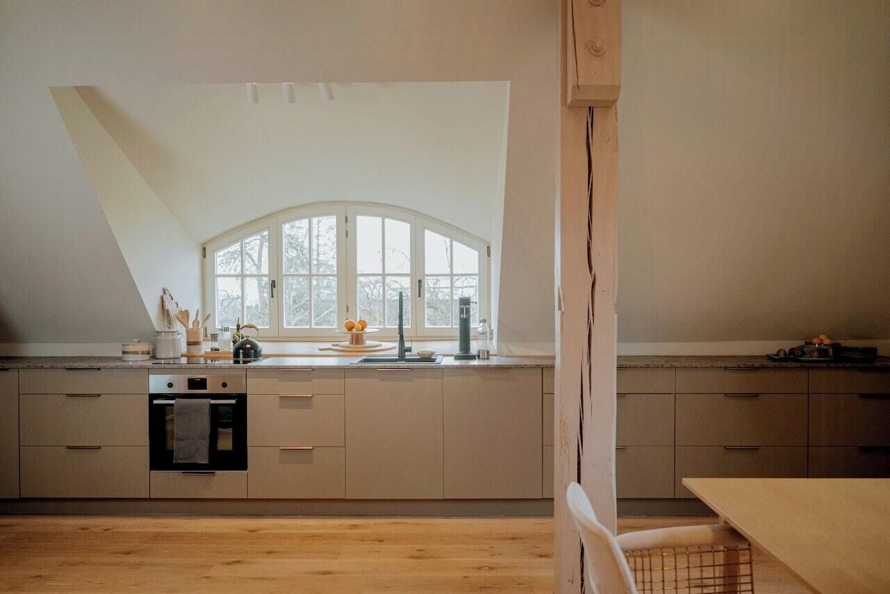 A modern kitchen with a skylight, built-in oven, and a large window.