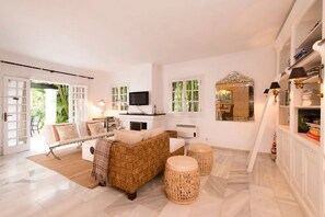 Ein geräumiges Wohnzimmer mit einer Couch, einem Hocker und einem Fernseher.