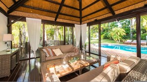 A spacious room with a large window, a pool, and a comfortable seating area. - Villa in palm tree plantation, near the beach. (Marbella)