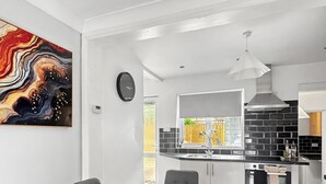 Een moderne keuken met een zwarte achterwand, witte kasten en een eetgedeelte met een marmeren tafel.