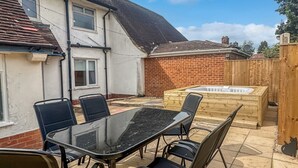 Een terras met een glazen tafel en stoelen, een jacuzzi en een bakstenen muur.