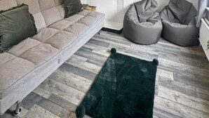 Een woonkamer met een bank, twee loungestoelen, een open haard, een televisie en een ingelijst kunstwerk.