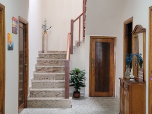 Eine Treppe mit Marmorstufen und Holzgeländern, ein Blumentopf, eine Holztür und ein Schrank mit Spiegel.