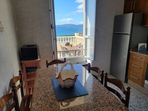 Eine Küche mit Meerblick, einem Esstisch, Stühlen, einem Kühlschrank und einer Mikrowelle.