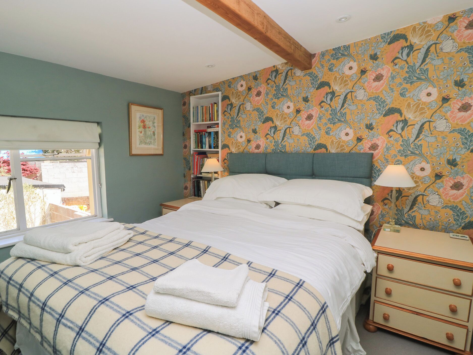 Quarto com cama, mesa de cabeceira, estante e janela.