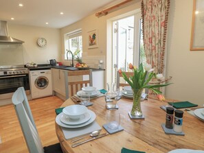 A kitchen with a stove, oven, washing machine, and a dining area with a table set for two. - 4 Duck Street (Dorchester)