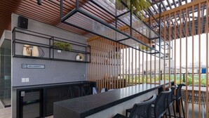 Uma área de bar moderna com balcão, banquetas pretas e um letreiro indicando 'Area Gourmet'.
