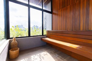 Ein Zimmer mit großem Fenster, einer Holzbänkl und gewebten Körben.