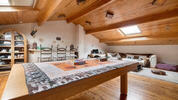 Un acogedor dormitorio en el ático con techo de madera, una mesa de comedor, un sofá y una estantería.