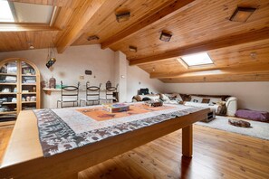 Une pièce mansardée chaleureuse avec un plafond en bois, une table à manger, un canapé et une bibliothèque.