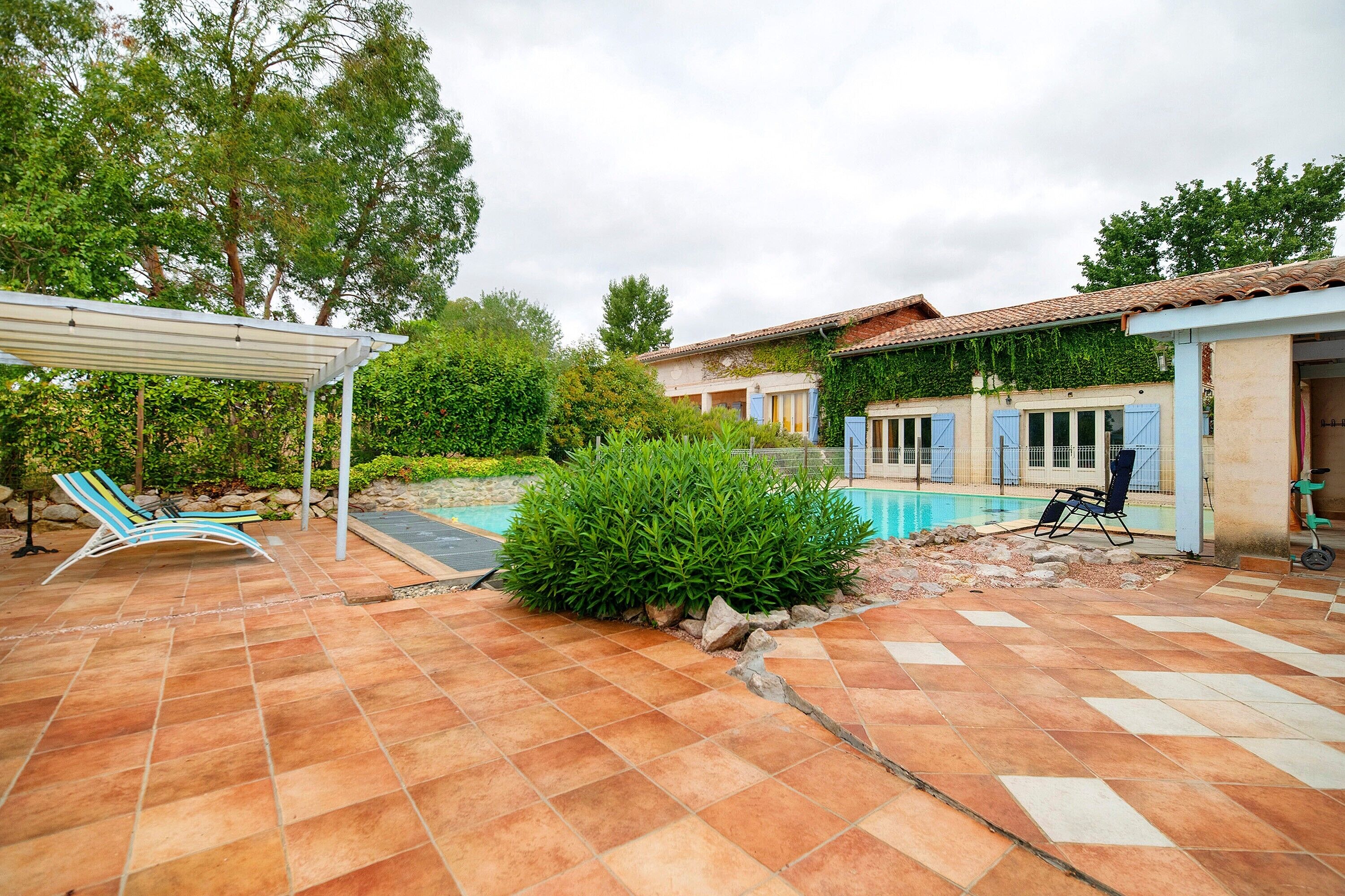 Propiedad residencial con piscina, mobiliario exterior y zona de patio techada.