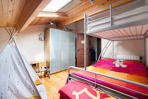 A bunk bed with a colorful quilt, a wooden wardrobe, a small table, and a tent-like structure. - Gîte de Gascogne – Sleeps 6 with Private Pool, Shared Terraces, and Wi-Fi (Vignaux)