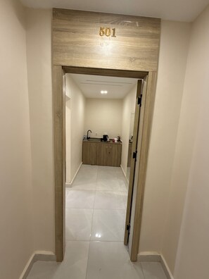 Een hal met een houten deurkozijn, een bord met het nummer '501', en een badkamer met een wastafel en kastjes.