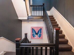 Eine Treppe mit schwarzem Geländer, Teppichstufen und einem Wandbild mit Schmetterlingen.