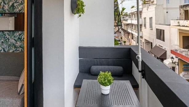 A balcony with a black umbrella, a small table, a potted plant, and a grey sofa. - Colonial Studio·Steps from Parque Colón |Yellowkey (Santo Domingo)